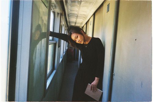 Free A woman leans in a train corridor, reflecting a contemplative mood. Stock Photo