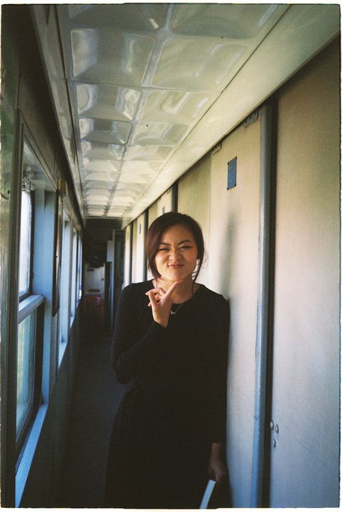 Free Young woman in black dress smiling in train corridor, natural lighting Stock Photo