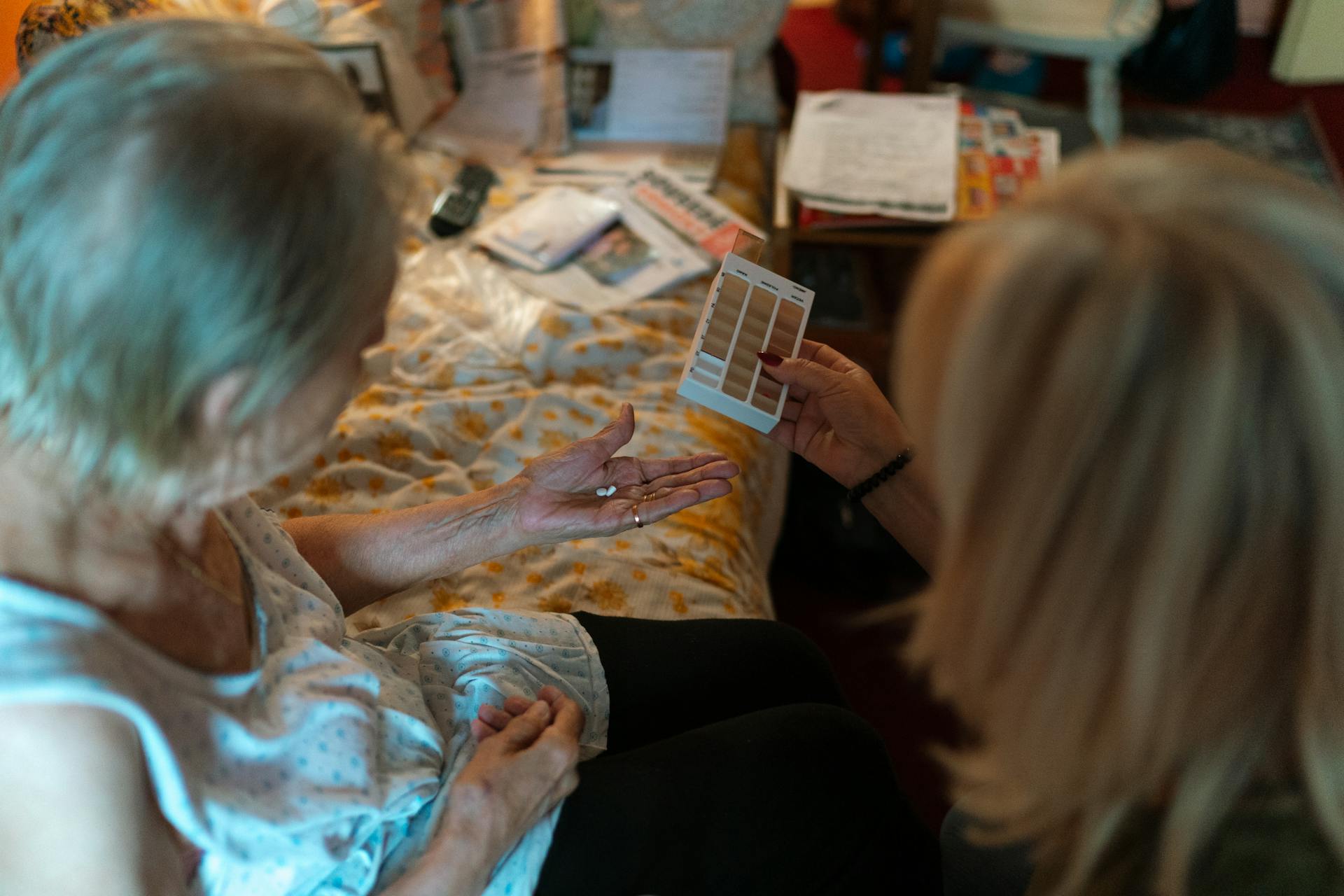 An elderly woman receives medication assistance at home, emphasizing home healthcare and caregiver support.