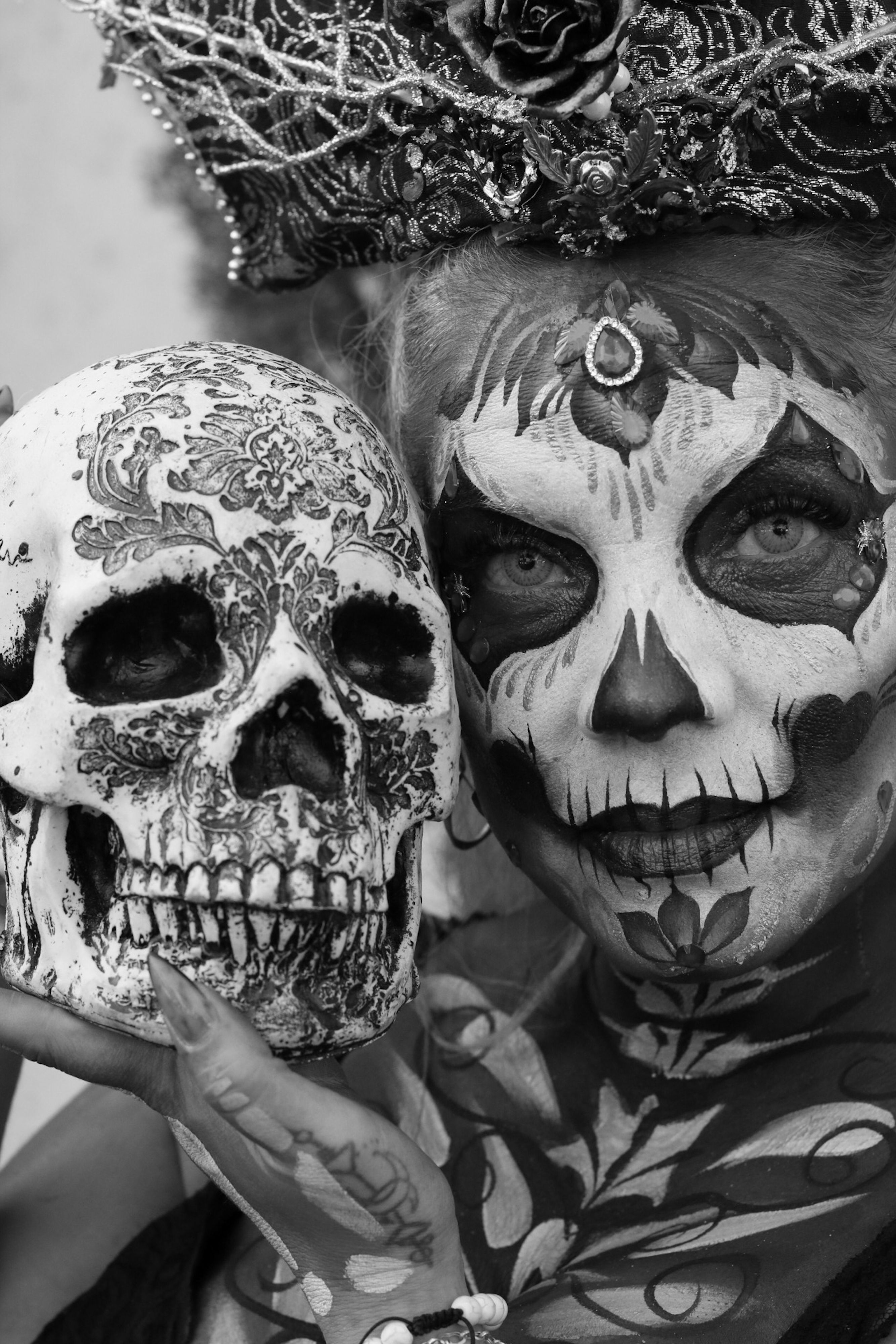 A captivating portrait of a woman with Day of the Dead makeup holding a decorated skull.