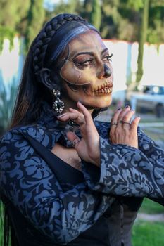 Woman with detailed skeleton face paint posing outdoors, showcasing elaborate artistry.