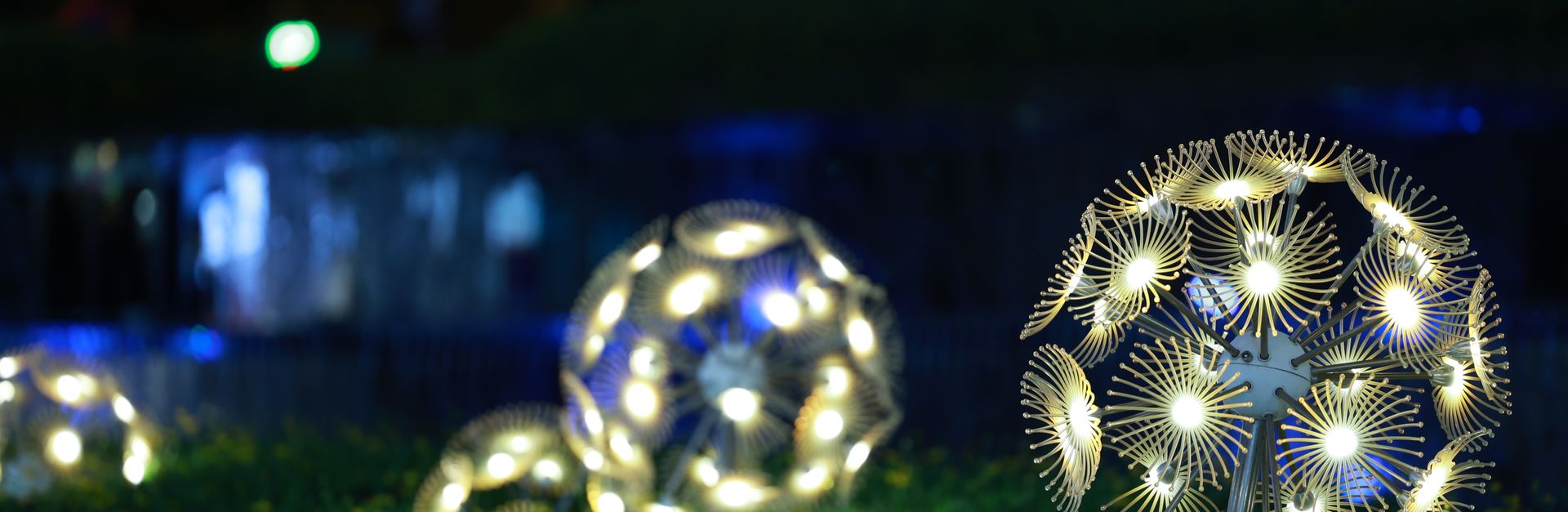 Artistic glowing spheres illuminate a garden at night, creating a magical atmosphere.