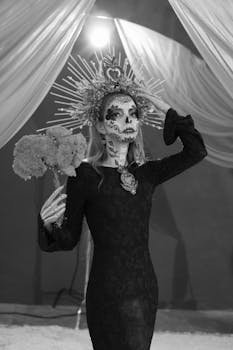 A woman in Day of the Dead makeup and attire holding flowers in a dramatic setting.