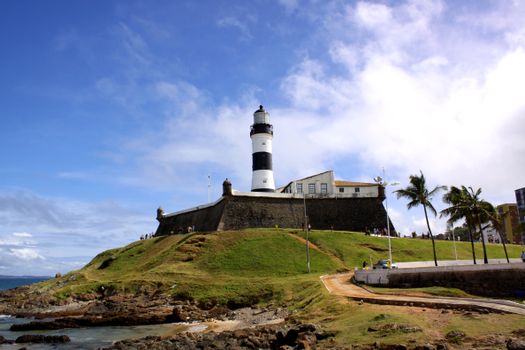 Dramatic view of Barra Lighthouse in Salvador, highlighting its historic architecture against a clear blue sky.