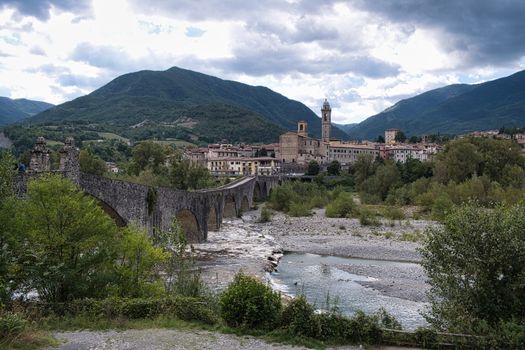 Stunning view of Ponte Gobbo and Bobbio village with lush mountains in Emilia-Romagna, Italy.
