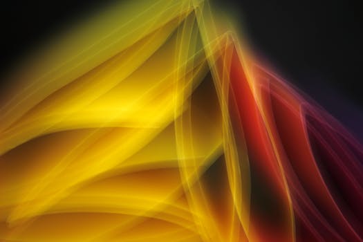 Dynamic abstract image showcasing vibrant yellow and red light waves in motion.