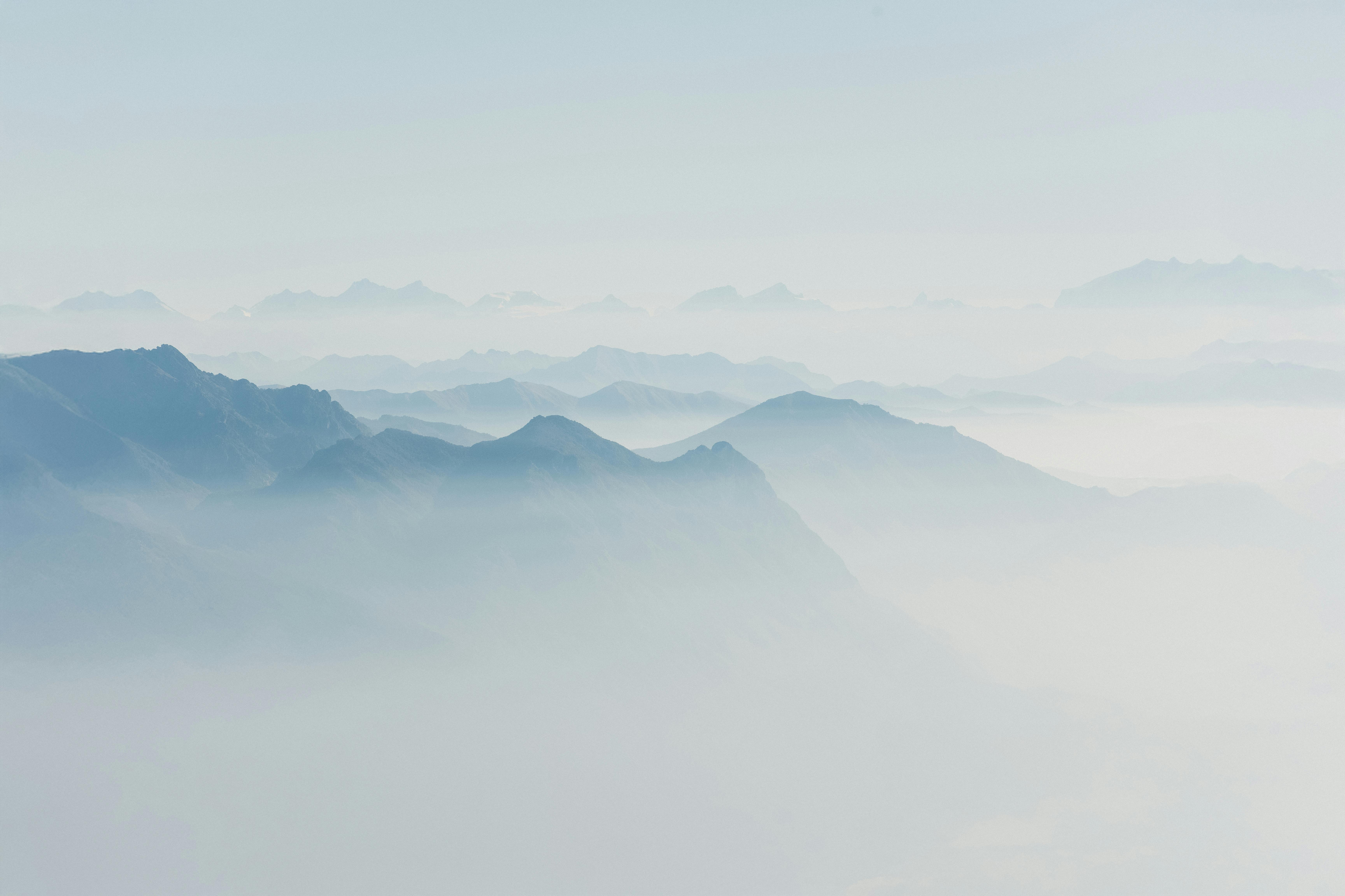 Peaceful aerial view of misty mountain ranges with soft lighting and tranquil mood.