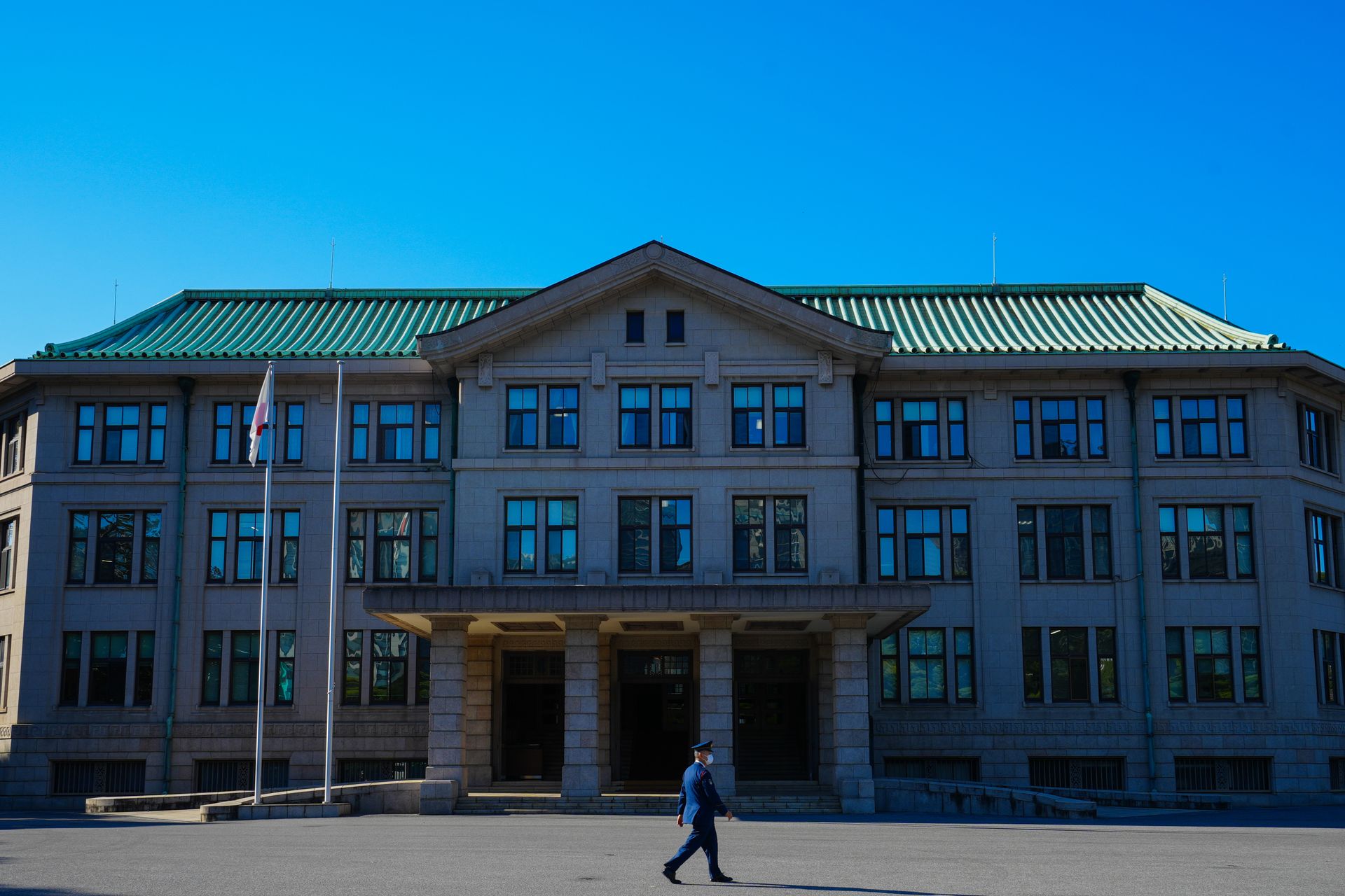An architectural view of a government building with a person walking past under a clear blue sky.
