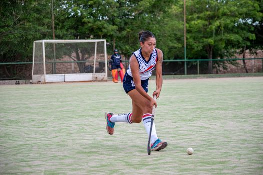 Captivating image of a female hockey player striking the ball on an outdoor field, showcasing athleticism and focus.