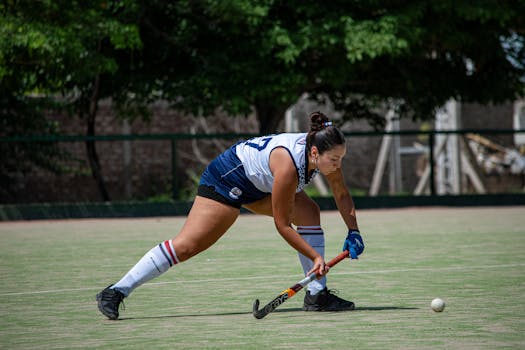 A female field hockey player concentrates as she prepares to strike the ball during a match.