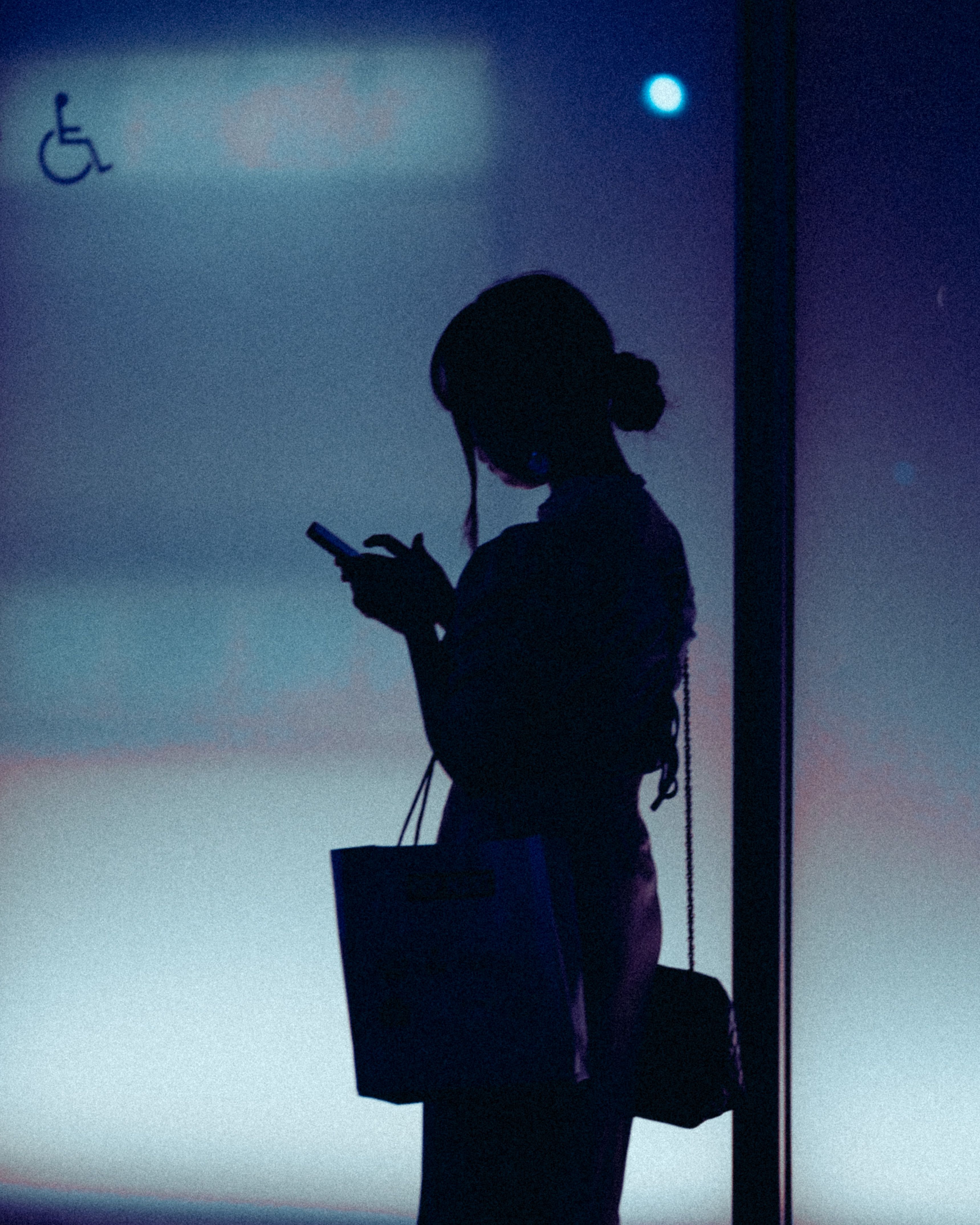 A woman silhouetted against a gradient background using her phone in Tokyo