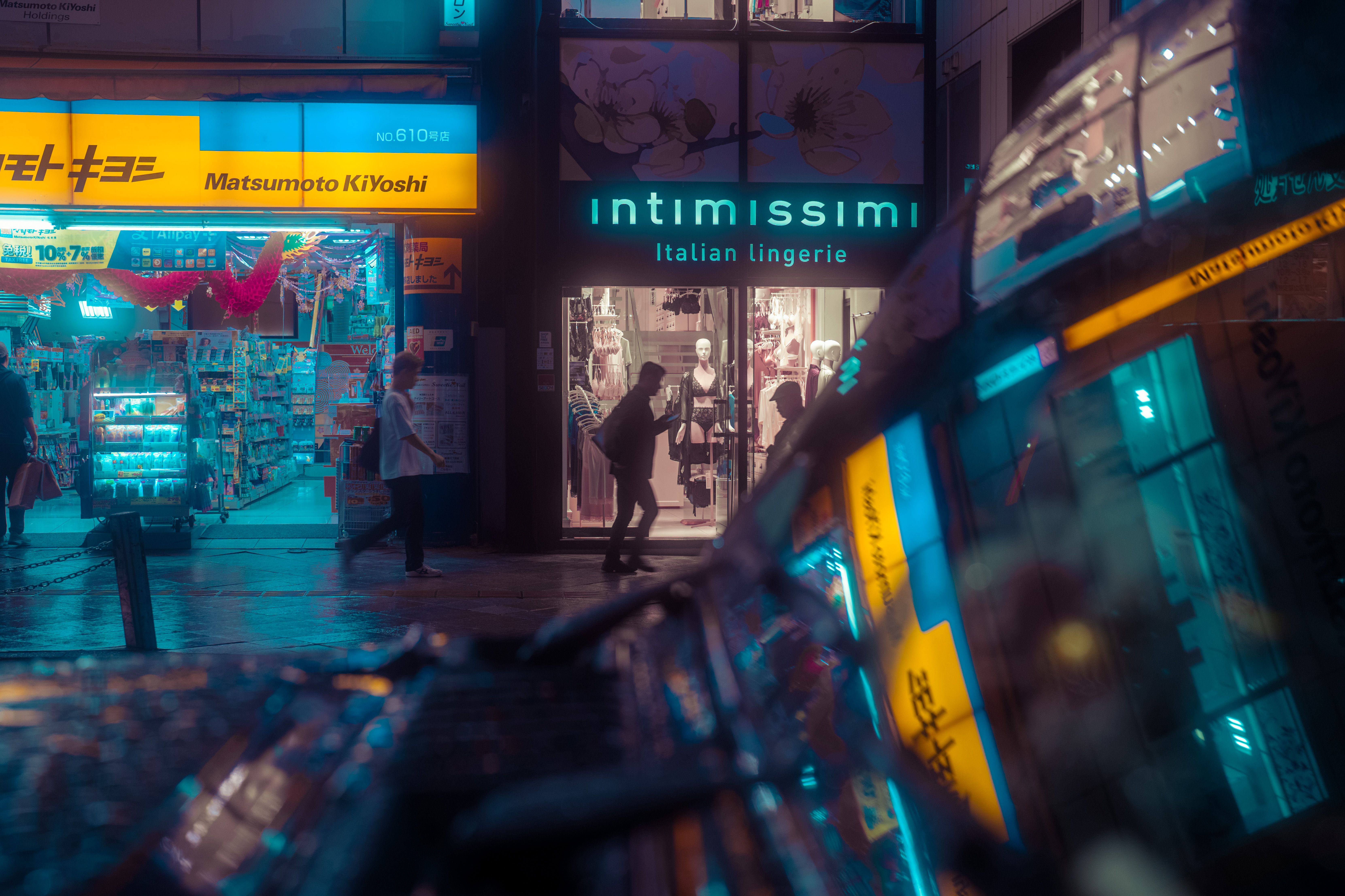 A vivid night scene in Tokyo showcasing neon-lit stores and reflections, capturing the urban nightlife.