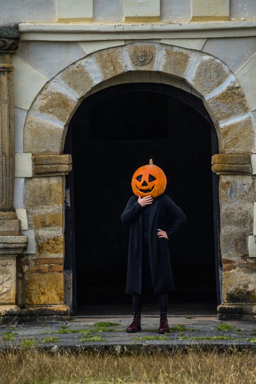 Free A mysterious figure with a pumpkin head stands in an ancient archway in Guasca, Colombia, creating a spooky Halloween vibe. Stock Photo