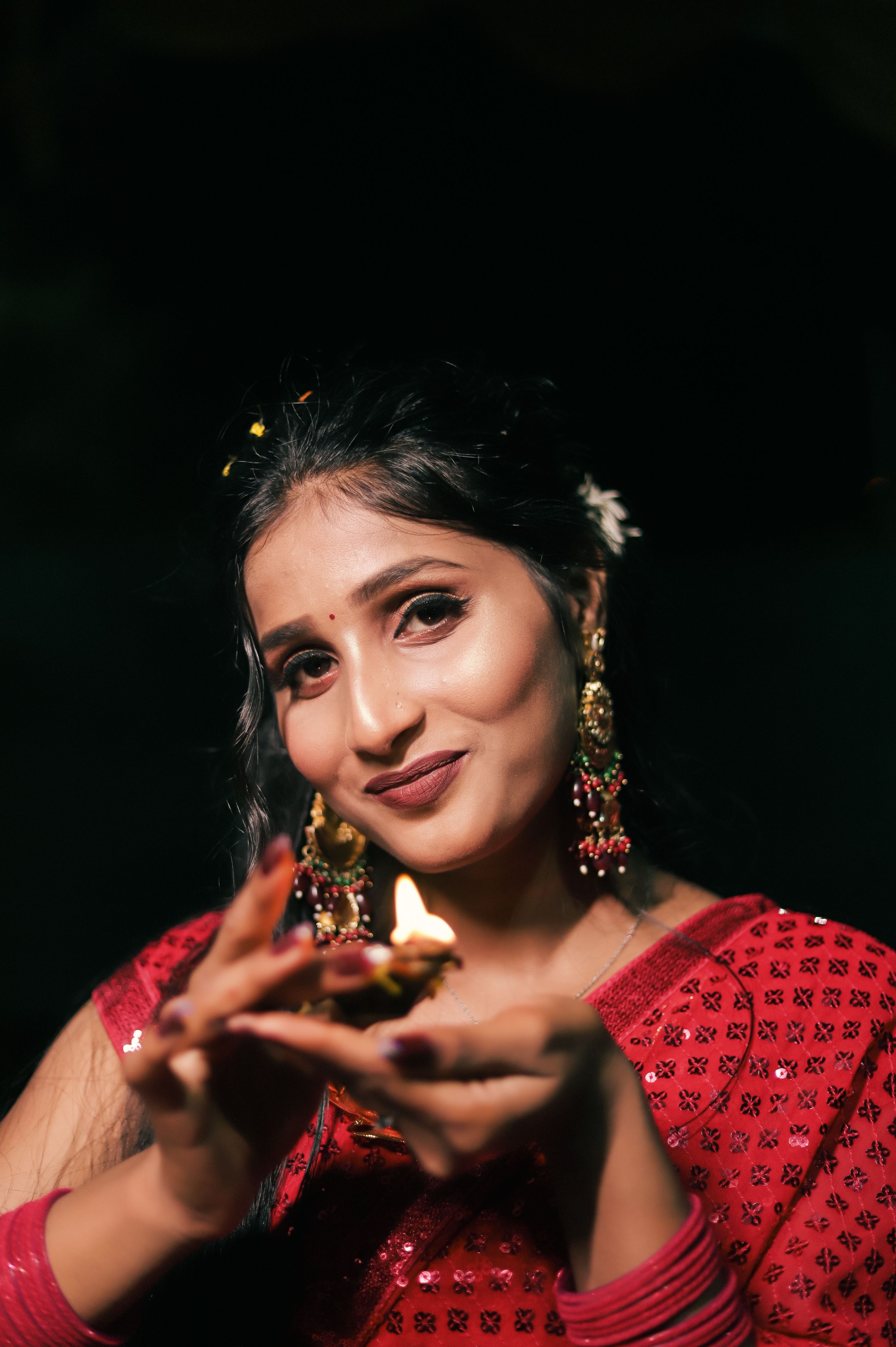 A beautiful South Asian woman holds a Diwali lamp, embodying the festive spirit in traditional attire.