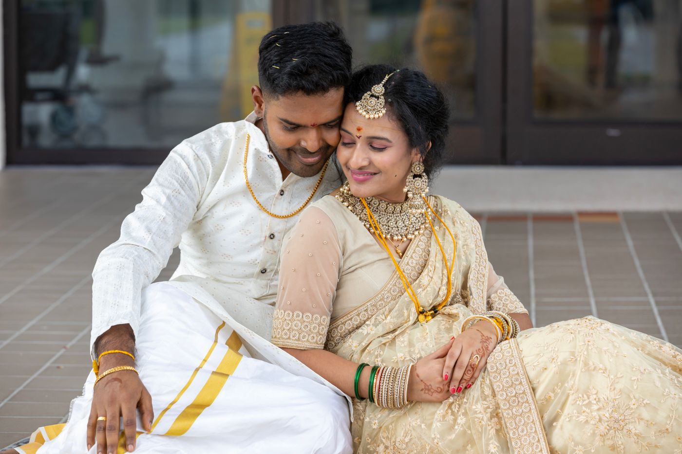 Elegant Kerala-style bride in a cream and gold saree with groom