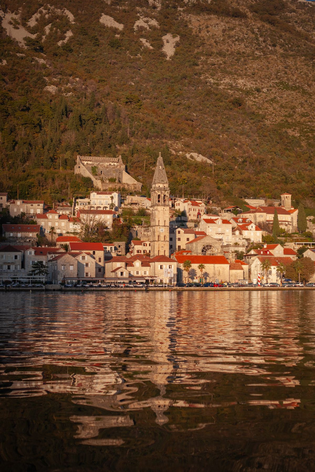 Perast waterfront and bell tower reflected in the Bay of Kotor
