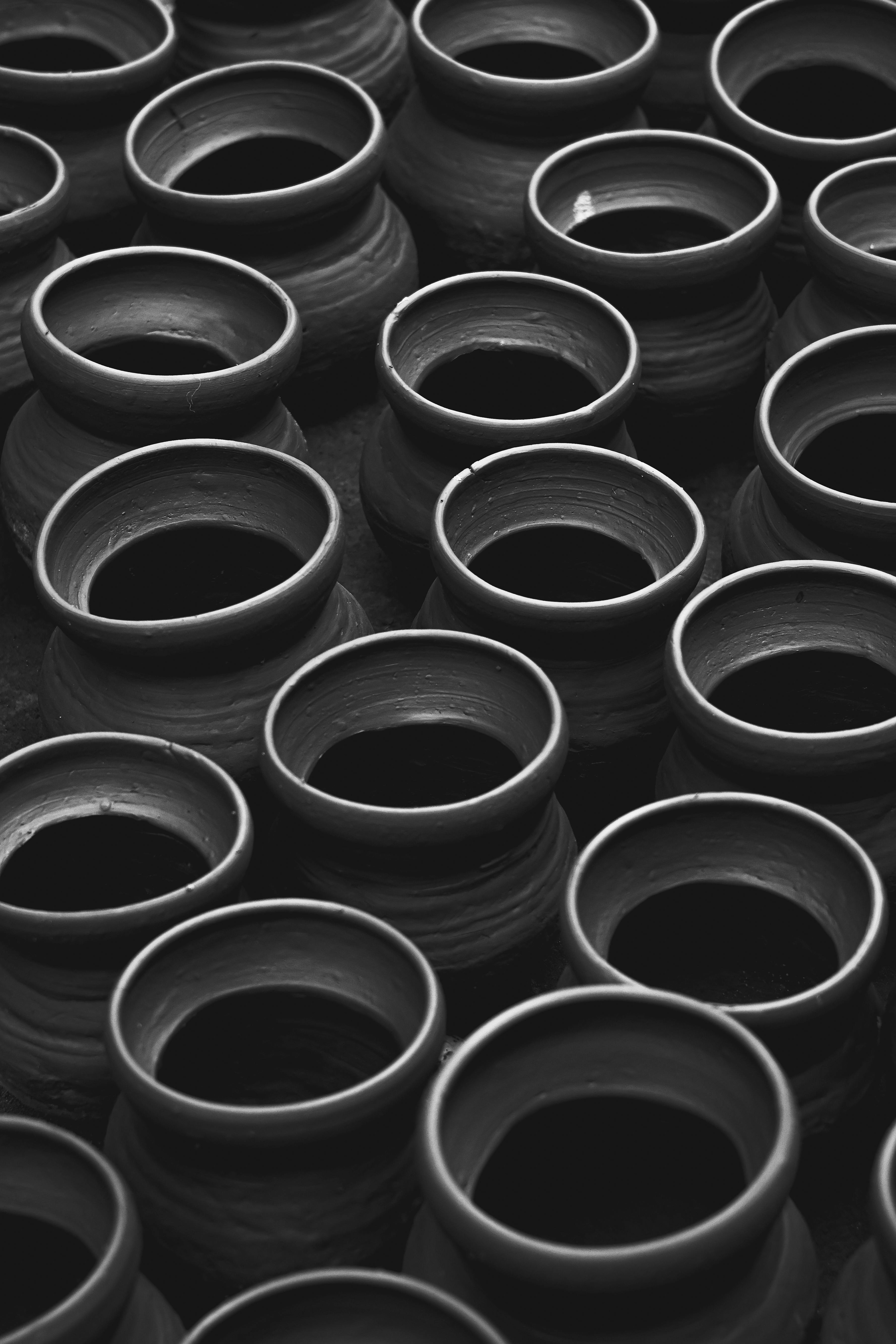 A black and white photo of clay pots arranged in rows, highlighting artisan craftsmanship.