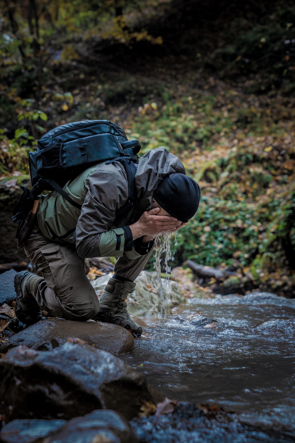 Hiker filtering and drinking water from a mountain stream