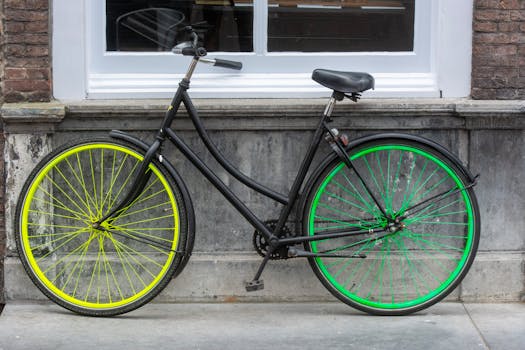 A black bicycle with vibrant green and yellow wheels leaning against a brick facade.