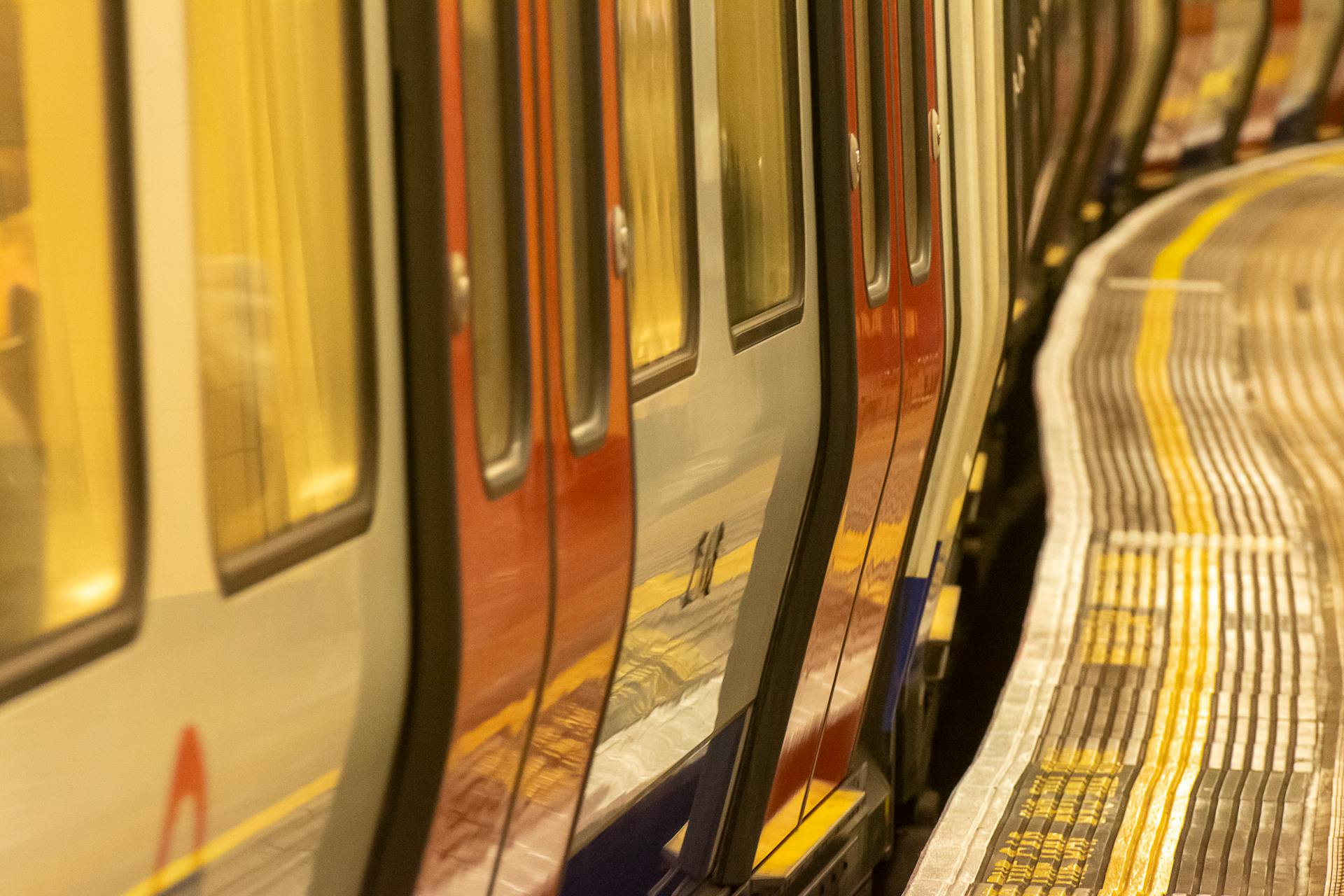 Curved London Underground platform with train in motion.