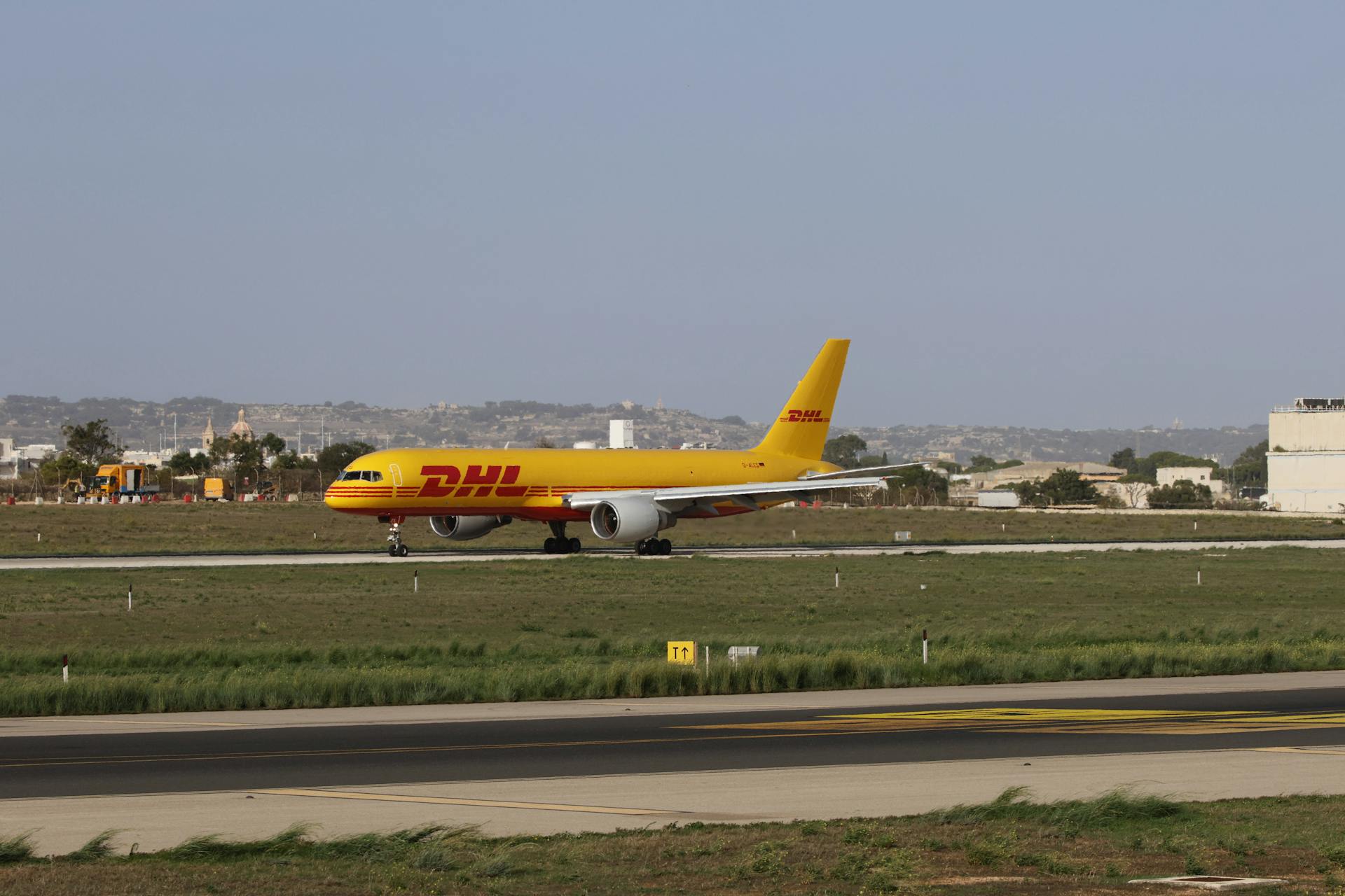 DHL cargo plane preparing for takeoff on a sunny runway, showcasing logistics and aviation.