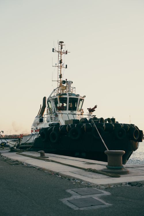Free Captivating view of a tugboat docked at a serene harbor during sunset, creating a calm atmosphere. Stock Photo