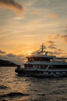 A luxury yacht sails on ocean waters at sunset, capturing tranquility and elegance.