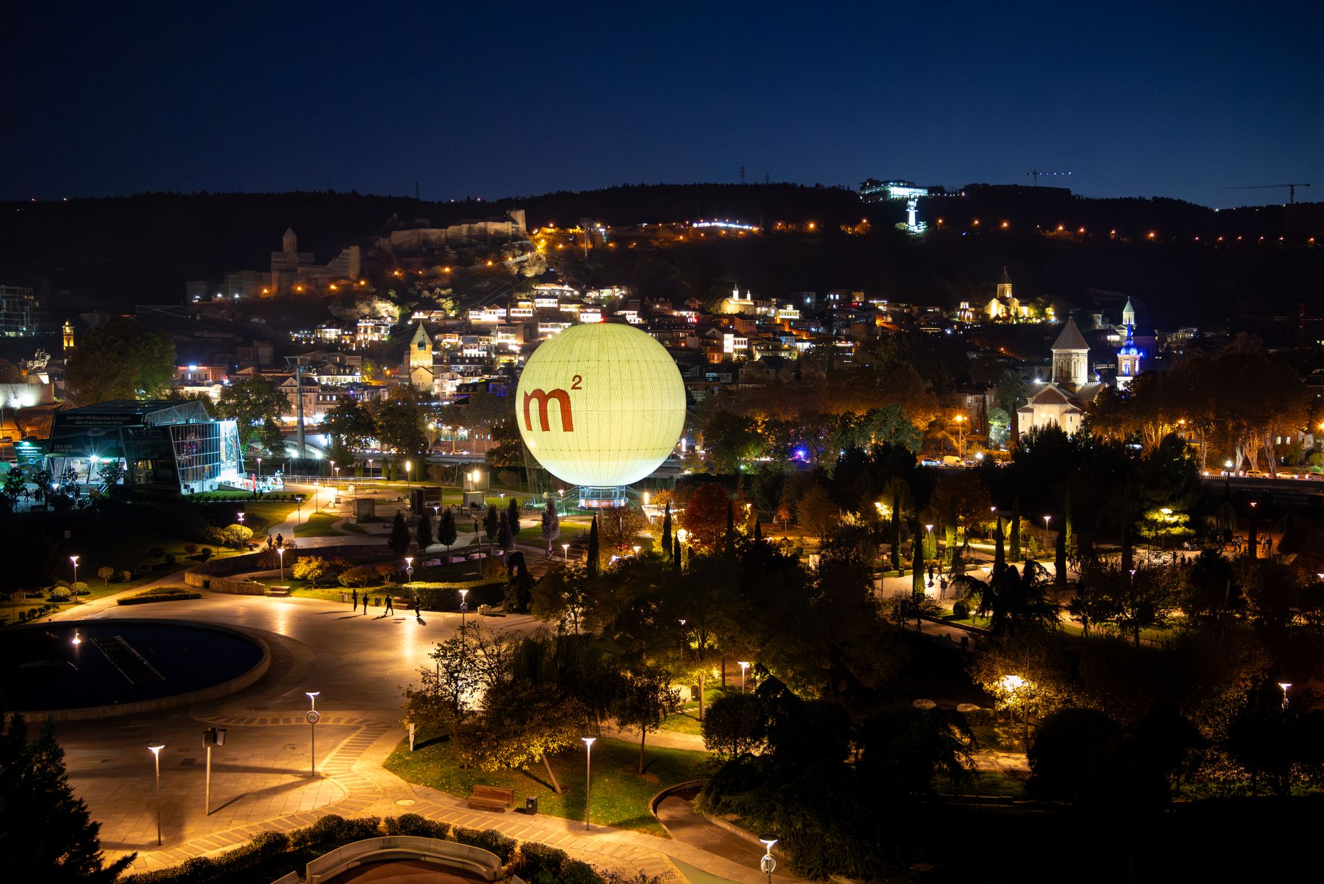 Stunning night view of Tbilisi, Georgia featuring an illuminated balloon and city lights.