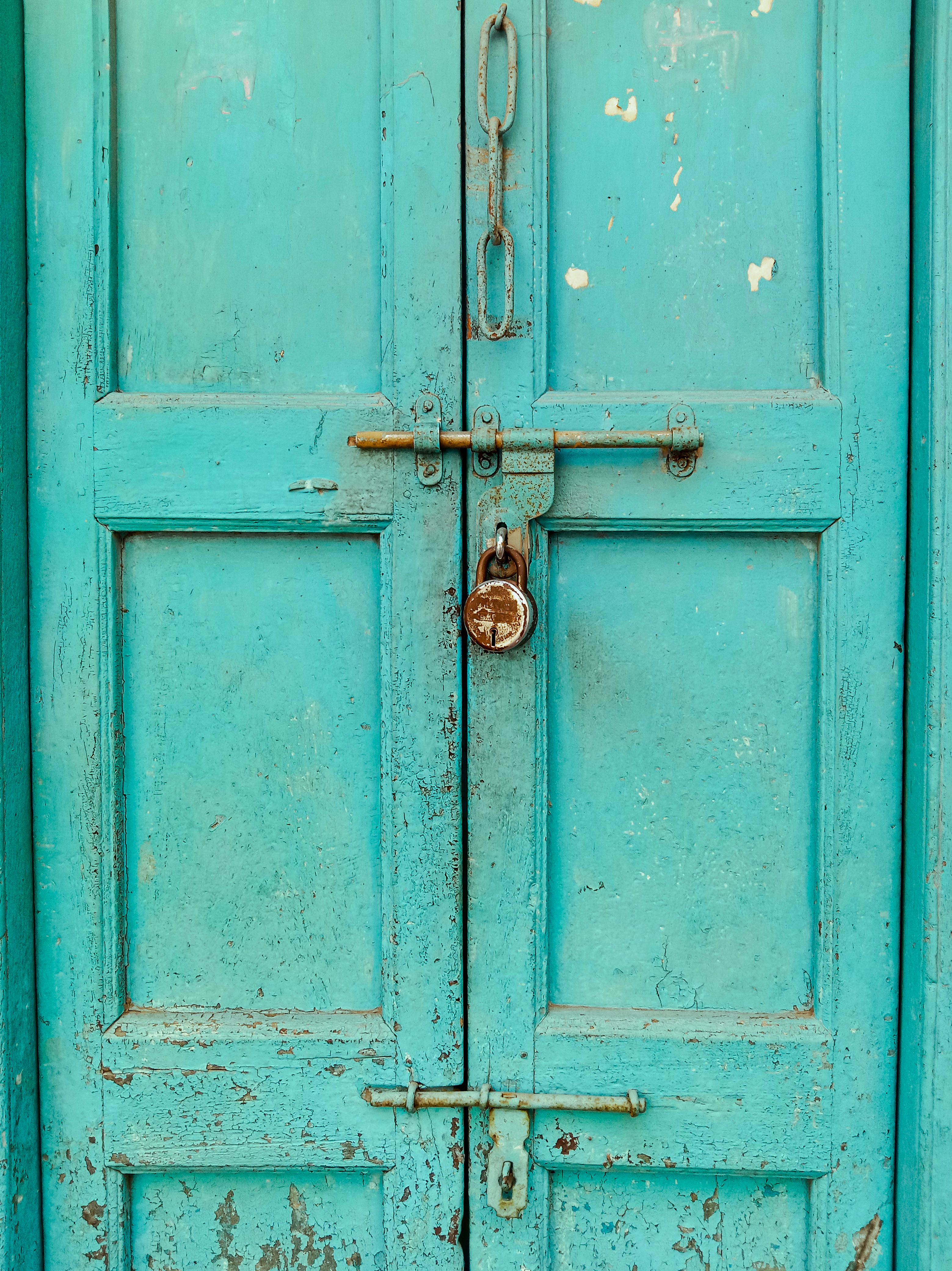 A rustic blue wooden door with a vintage padlock, exuding an antique charm.