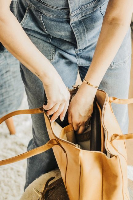 Woman arranging essentials inside a leather tote bag