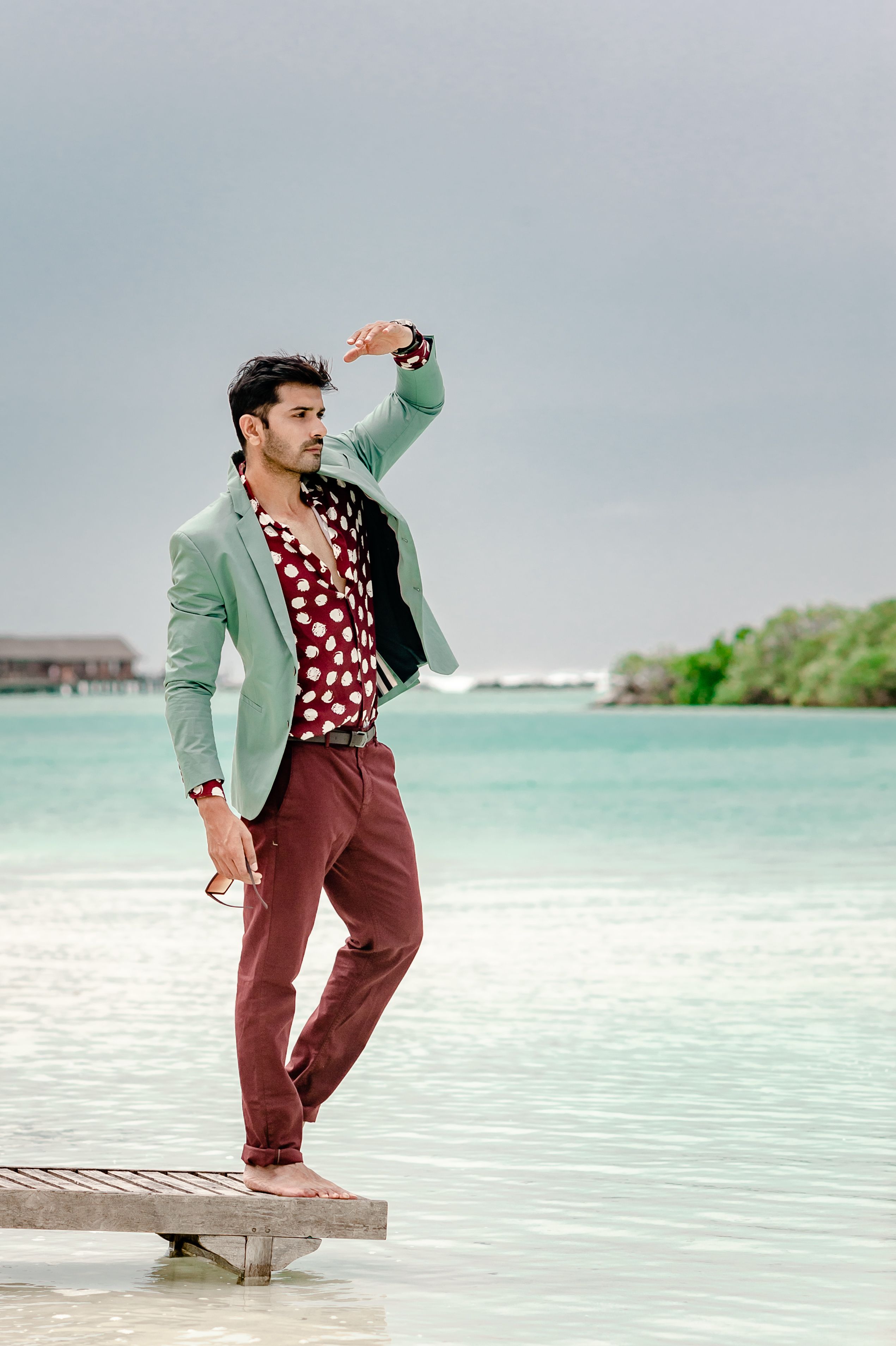Stylish man posing on a Maldives beach deck, capturing tropical fashion vibes.