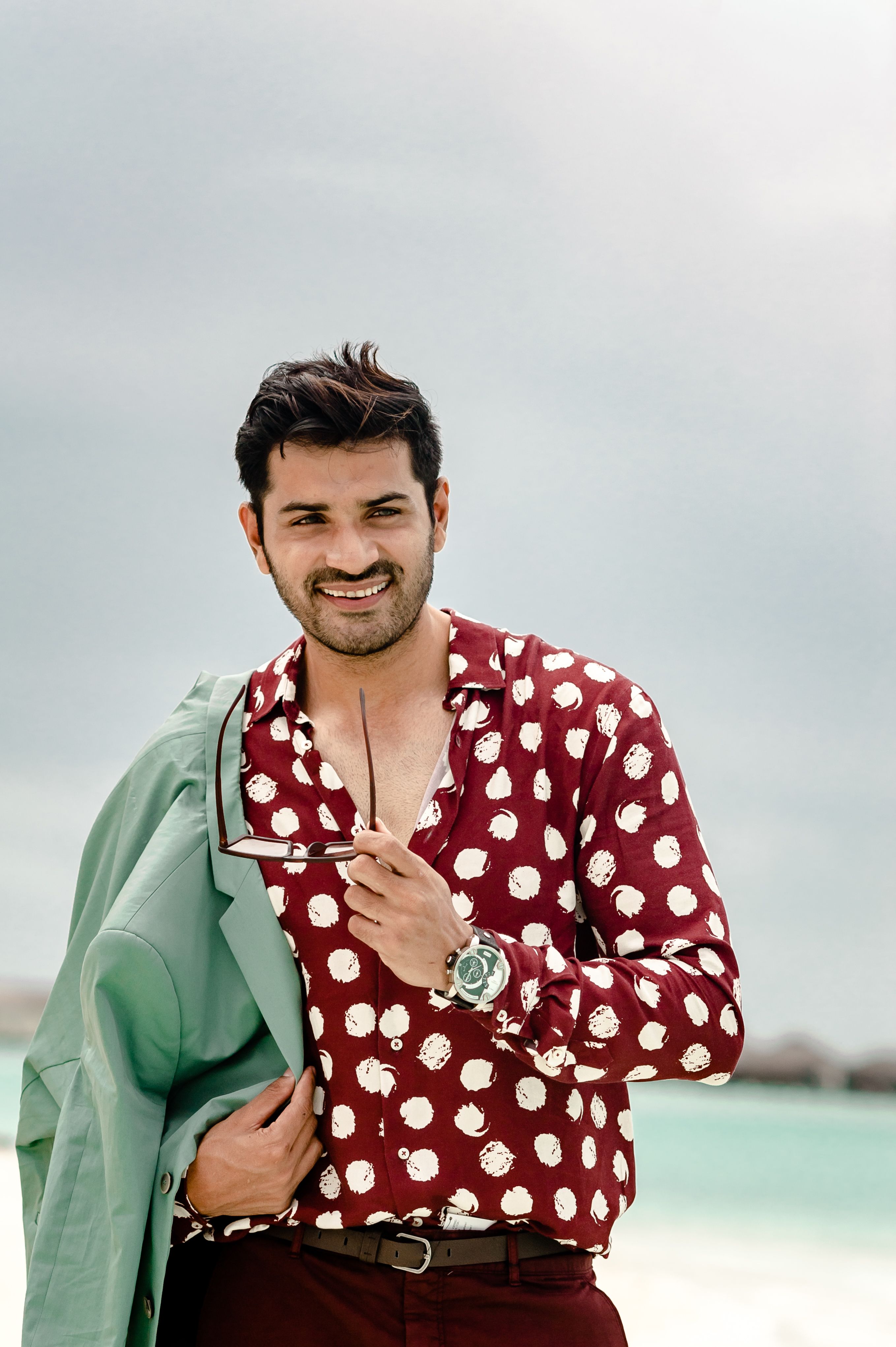 Fashionable man enjoying a tropical beach vacation with stylish attire.