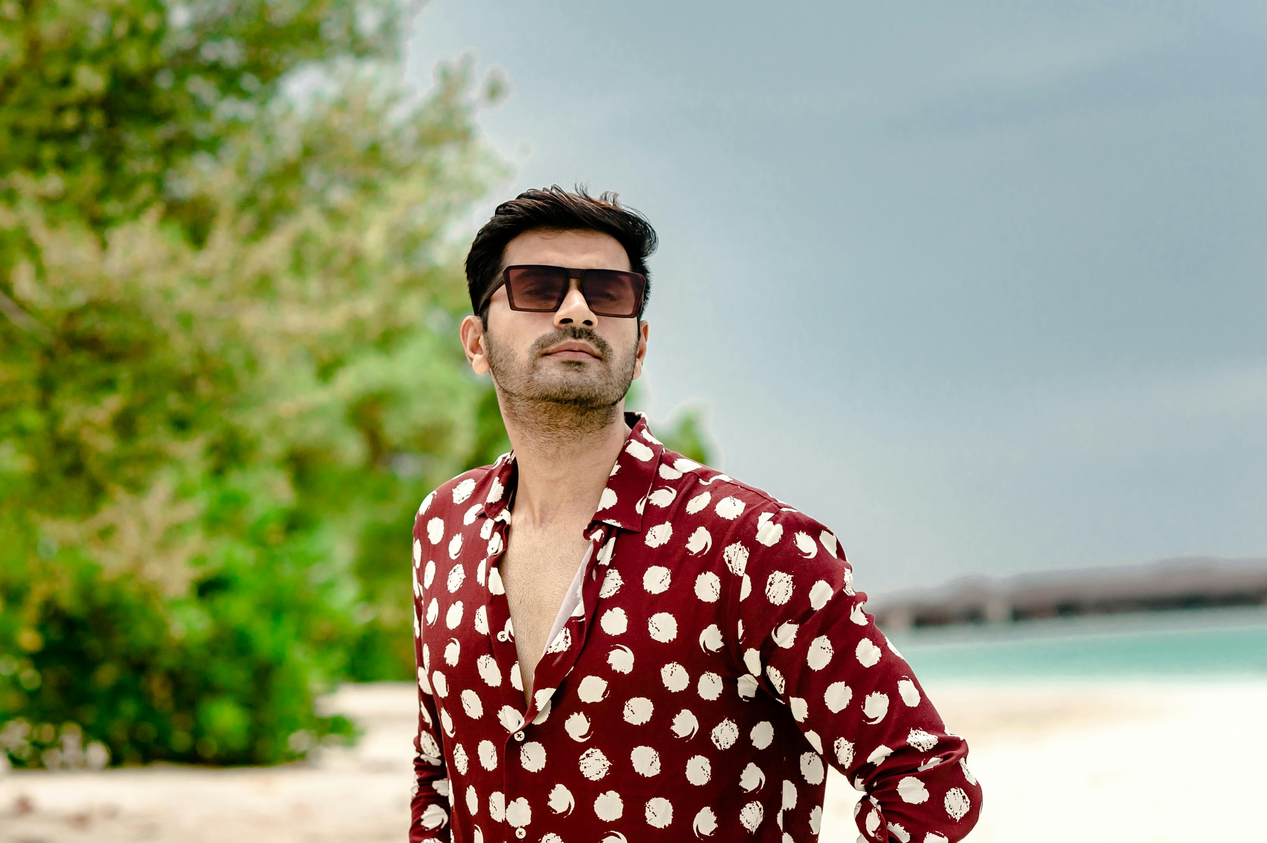 Fashionable man wearing sunglasses poses on a sunny Maldives beach.