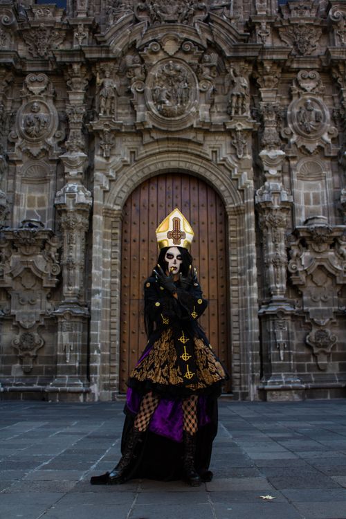 Free A gothic performer poses in front of an ornate historical building, showcasing detailed costume and architecture. Stock Photo