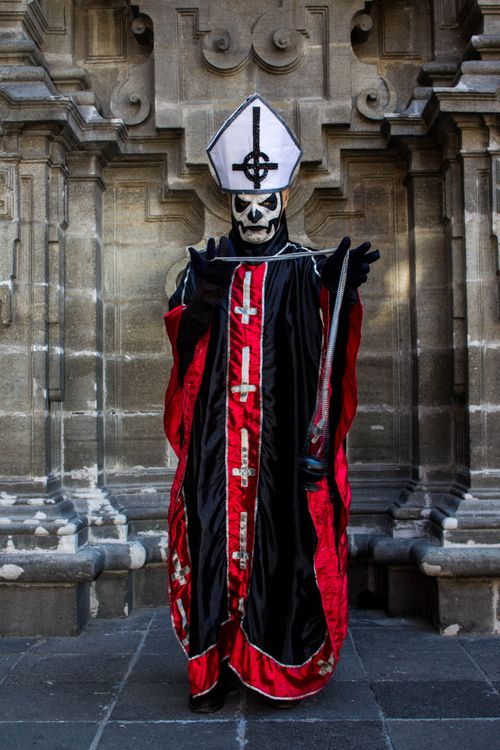 Free Person in ornate gothic robe with skull makeup against historic stone architecture. Stock Photo