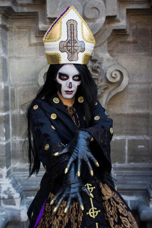 Free Gothic figure in intricate costume posing dramatically against historical architecture. Stock Photo