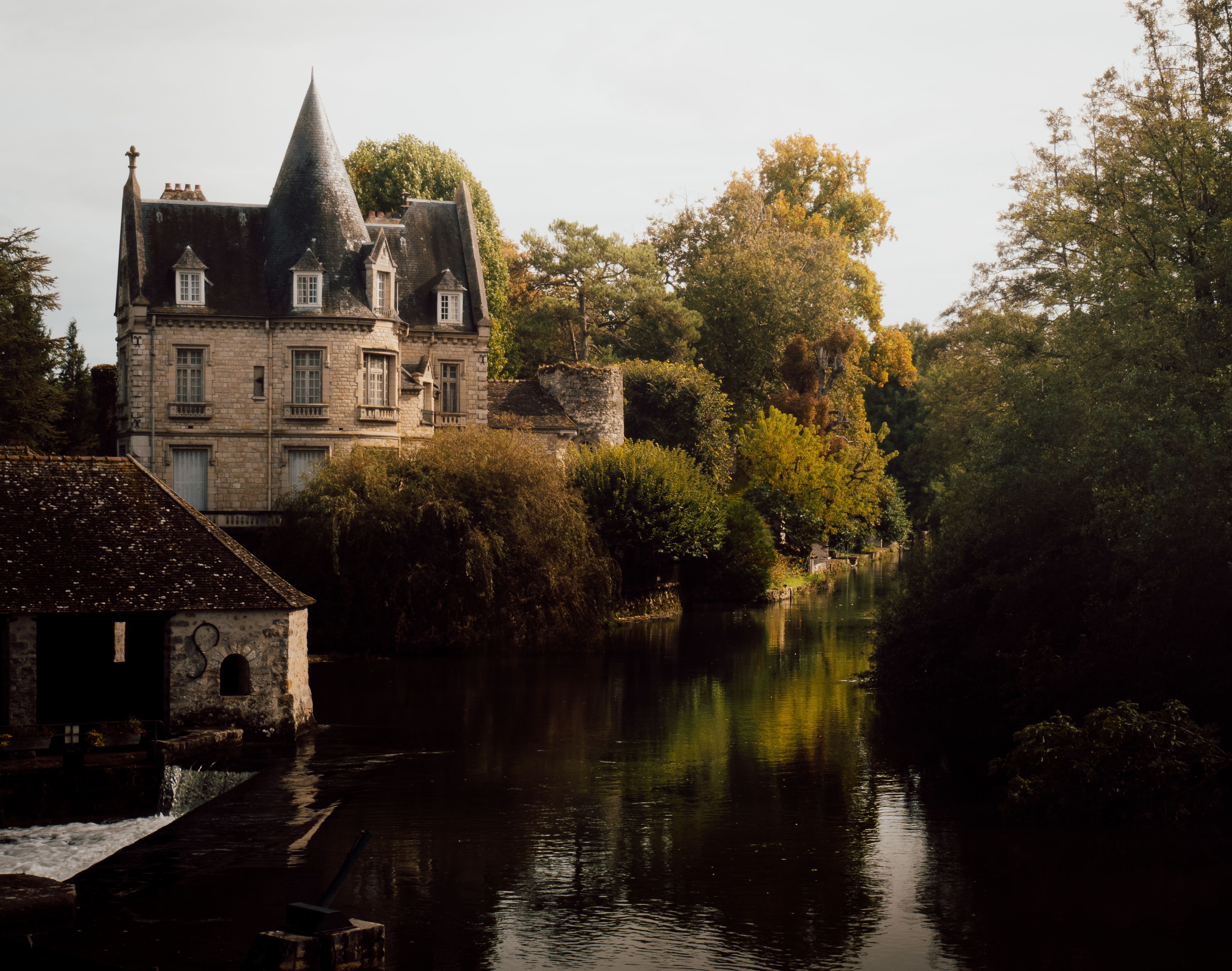 Picturesque autumn view of a chateau by the river in Moret-Loing-et-Orvanne, France.