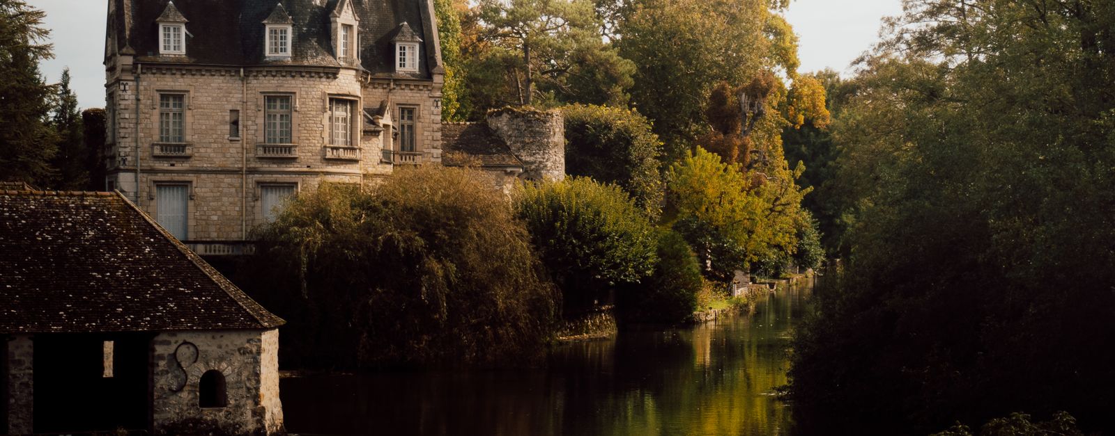 Picturesque autumn view of a chateau by the river in Moret-Loing-et-Orvanne, France.
