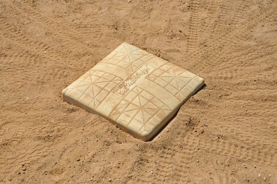 A detailed close-up of a baseball base on a dirt field, showing tire tracks. — Photo by Renee B on Pexels