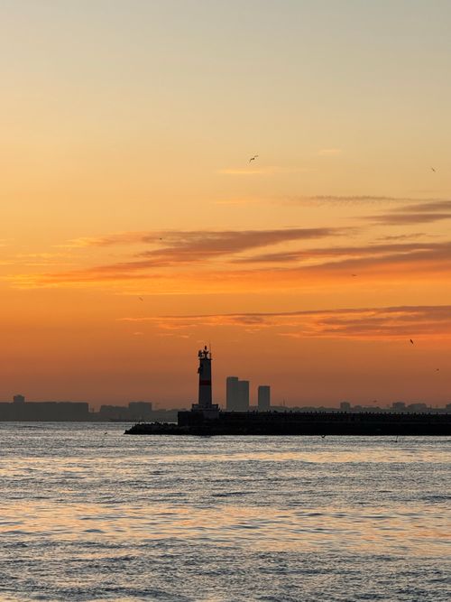 Free Stunning view of Istanbul lighthouse with a vibrant sunset sky reflecting on calm waters. Stock Photo