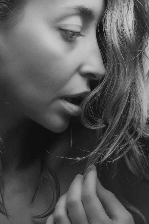 Free Intimate grayscale close-up of a woman with flowing hair, evoking a classic and artistic feel. Stock Photo