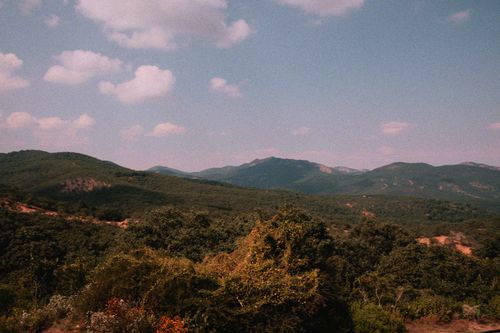Free Breathtaking view of lush green mountains under a clear blue sky with fluffy clouds. Stock Photo
