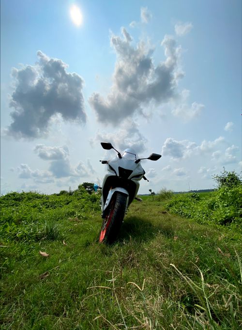 Free A sport bike on a grassy path under a bright blue sky with clouds, showcasing nature and adventure. Stock Photo