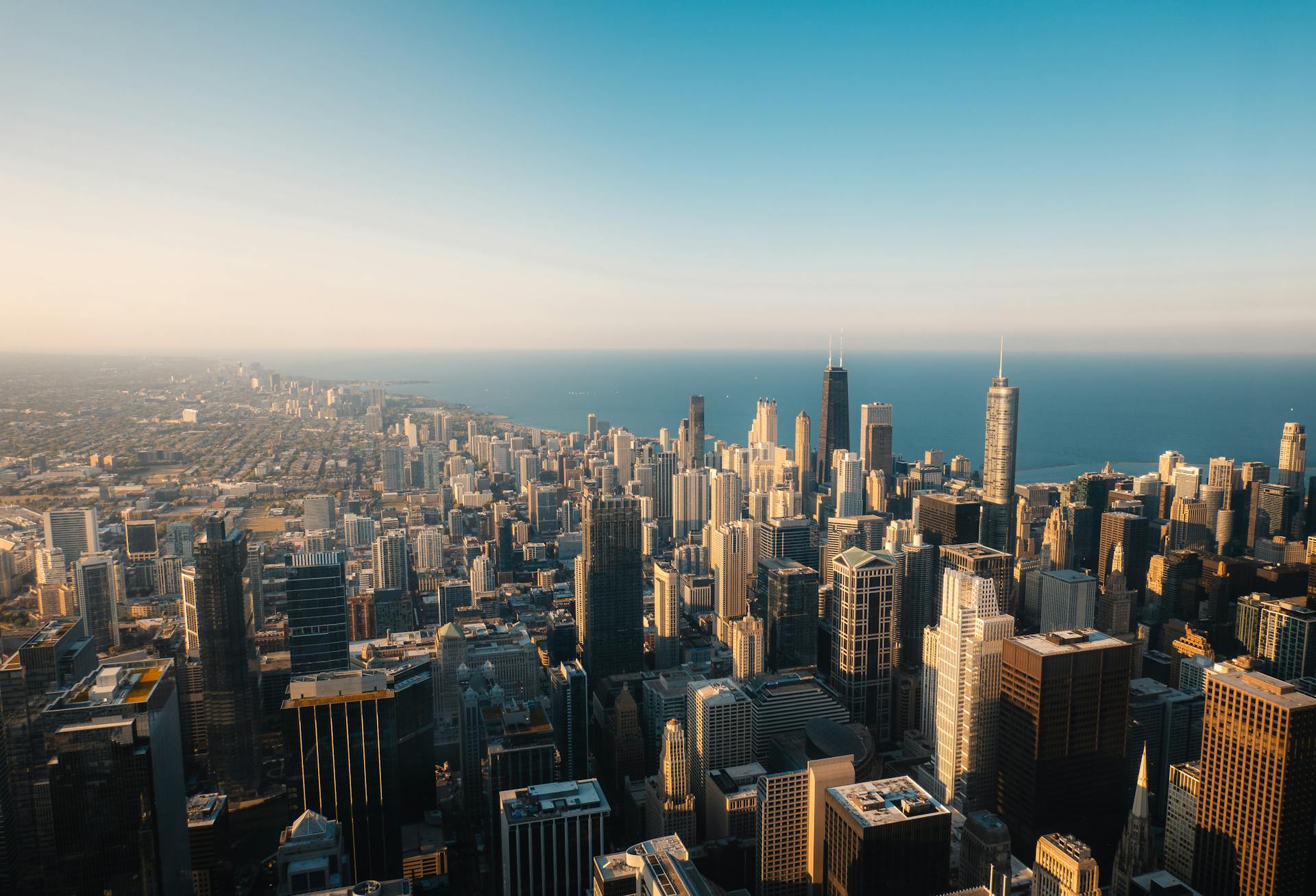 A breathtaking aerial shot capturing the iconic Chicago skyline with a clear horizon and Lake Michigan.