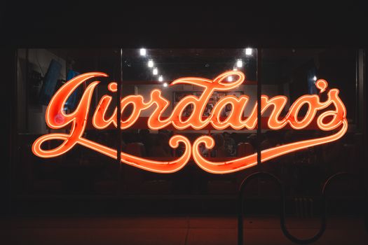 A vibrant neon Giordano's sign glowing at night, capturing urban nightlife.