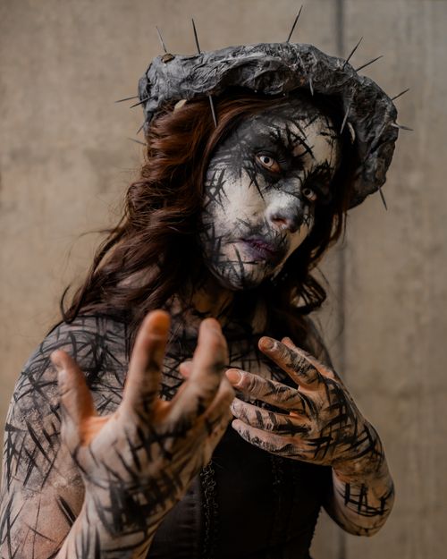 Free A female with surreal makeup and dark artistic theme posing with an expressive gesture. Stock Photo
