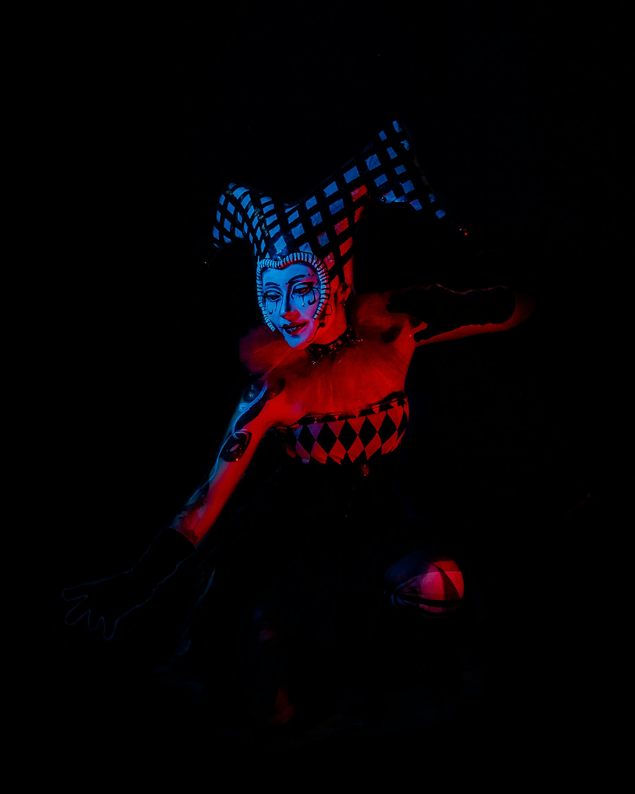 Free A striking surreal portrait featuring a jester costume with intricate makeup in dark tones. Stock Photo