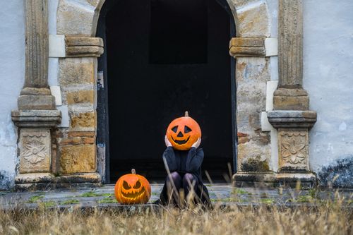 Free Person wearing pumpkin head near historical stone doorway in Guasca, Colombia. Stock Photo