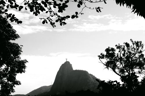 Free Silhouetted view of Christ the Redeemer statue in Rio de Janeiro with lush foreground and mountain backdrop. Stock Photo