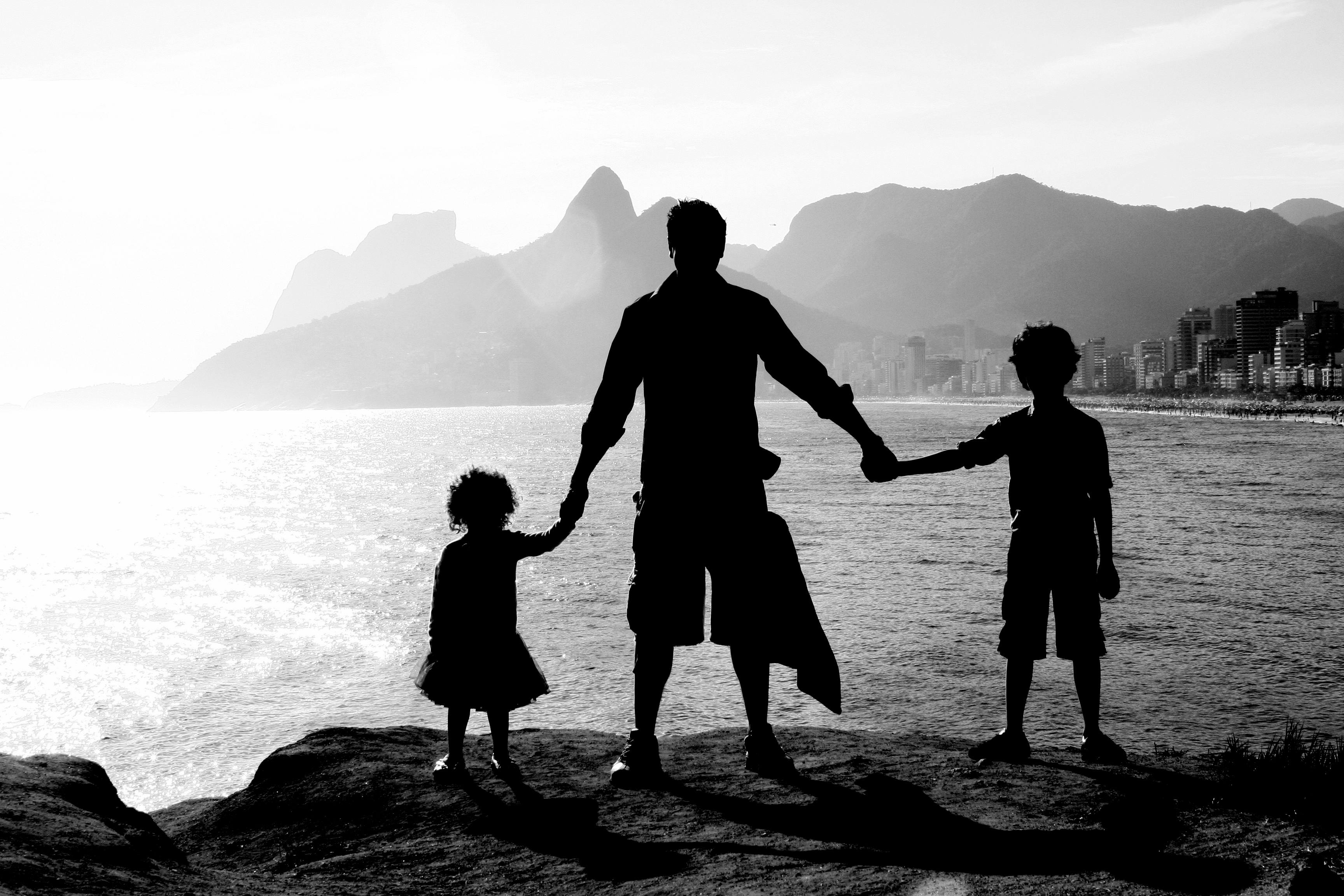 A family silhouetted against the sunset at Ipanema Beach in Rio de Janeiro, Brazil.